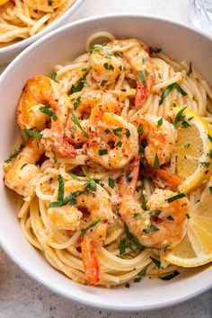 two bowls of pasta with shrimp and lemon garnish