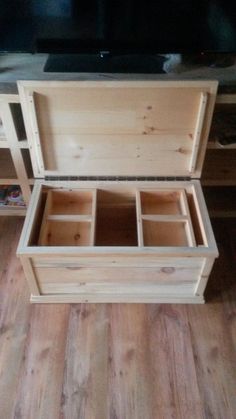 an empty wooden chest sitting on top of a hard wood floor next to a tv