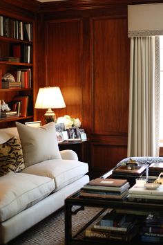 a living room filled with furniture and bookshelves next to a window covered in curtains