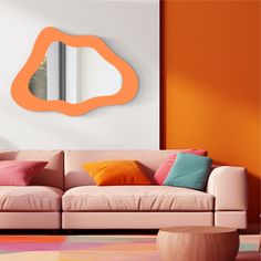 a living room with an orange mirror on the wall and pink couch in front of it