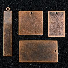 three pieces of metal sitting on top of a black surface with tags attached to them