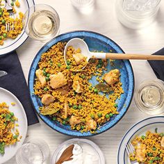 a blue plate topped with rice and chicken next to plates of food on top of a white table