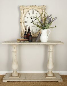 a table with a clock and some bottles on it next to a vase filled with flowers