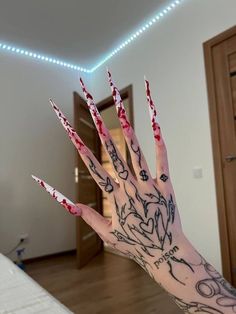 a person's hand with red and black nail polish holding up their nails in front of the camera