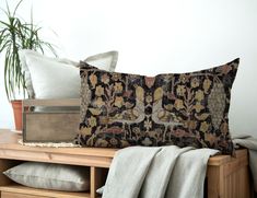 a pillow sitting on top of a wooden table next to a potted plant in a vase