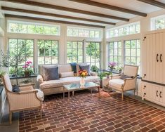 a living room with brick flooring and large windows on the side of the wall