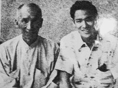 an old black and white photo of two men sitting next to each other in front of a wall