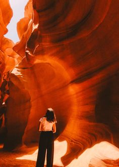 a woman standing in the middle of a canyon looking up into the sky with her hands on her hips