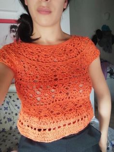 a woman is wearing an orange top with holes on the front and back, while she has her hands in her pockets