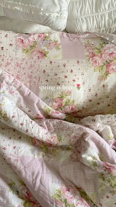 an unmade bed with pink flowers on it