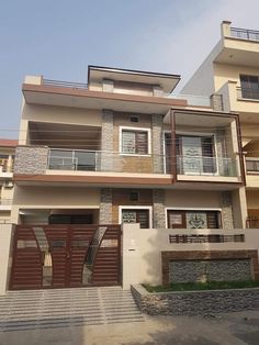 a two story house with brown doors and balconies on the second floor is shown