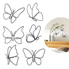 four metal butterflies on a shelf next to a vase