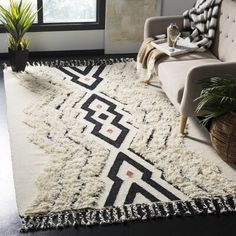 a living room area with a couch, chair and rug on the floor in front of a window