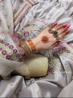 a close up of a person's hand with jewelry on it, wearing a dress