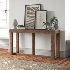 a wooden table with two pictures on top of it next to a rug and window