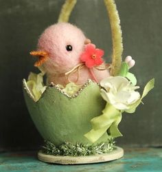 a small pink bird in a green basket with flowers