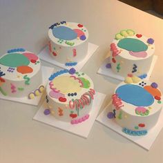 four decorated birthday cakes sitting on top of each other in front of a white table