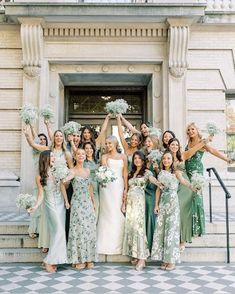 a group of women standing next to each other in front of a building holding bouquets