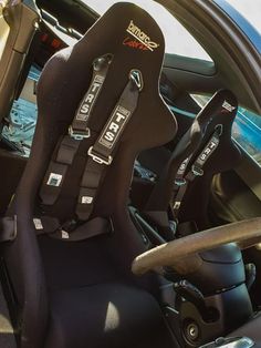 the interior of a car with black leather seats and steering wheel, in front of an open door