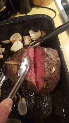 a person is cutting up some meat in a pan with cloves and garlic