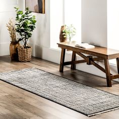 a wooden bench sitting on top of a hard wood floor next to a potted plant