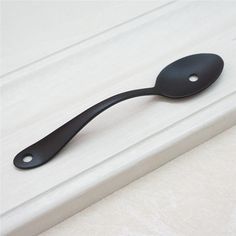 a black spoon sitting on top of a white counter