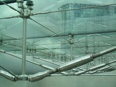 the inside of a glass building with metal pipes