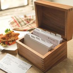 a wooden box filled with files next to a plate