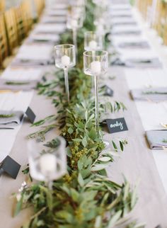 a long table with candles and greenery on it