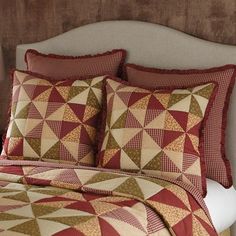 a bed with red and tan quilted bedspread, pillows and headboard