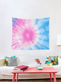 a pink and blue tie - dyed wall hanging over a white couch