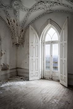 an empty room with two open doors leading to the other side, in front of a large window