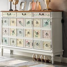 a white dresser with many drawers and lamps on top