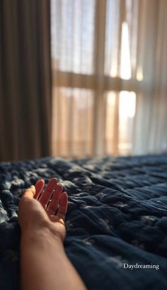 a person's hand resting on top of a bed