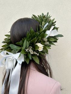 a woman with long hair wearing a white flower and ribbon headpiece on top of her head