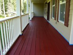 a porch with red wood floors and white railing