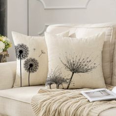 two pillows with dandelions on them sitting on a couch