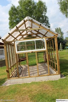 a small wooden structure with windows in the grass