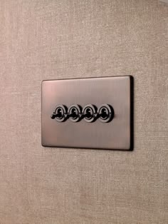 a close up of a metal button on a beige fabric wall with three circles in the middle