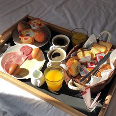 a tray filled with food and drinks on top of a bed