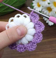 a crochet flower being worked on by someone using a knitting needle and thread