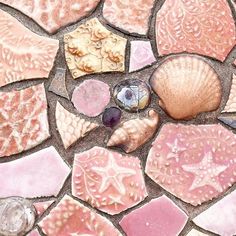 shells and seashells are arranged on a mosaic tile floor in pink, white, and grey colors