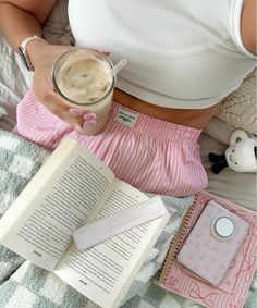 a woman laying in bed with an open book and cup of coffee