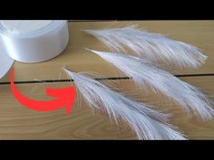 some white feathers are on a table next to a roll of tape