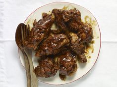 a white plate topped with meat covered in brown sauce next to a knife and fork