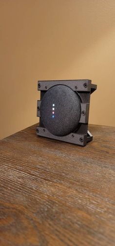 a speaker sitting on top of a wooden table next to a light brown colored wall