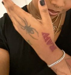 a woman with a spider tattoo on her arm making the peace sign and holding up her hand