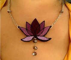 a woman wearing a necklace with a flower design on the front and back of it