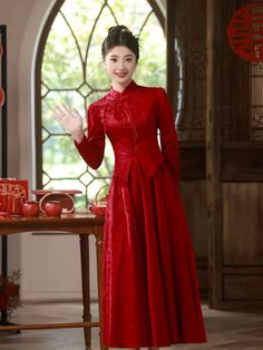 a woman in a red dress standing next to a table with an apple on it