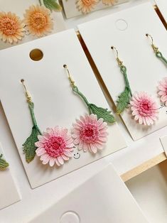 several flower earrings are displayed on cards with flowers in the middle and one is pink